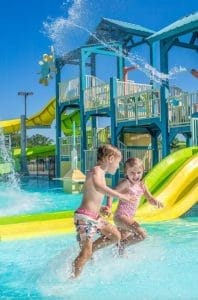 A boy and girl playing at a water play park