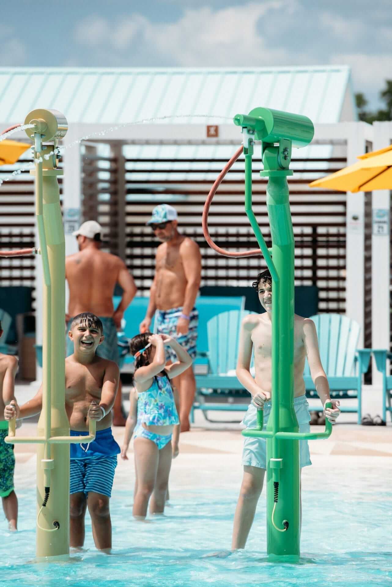Two teen boys point the beanstalk water blasters at other water players and participate in water wars at the water play structure by Interactive Play at the Camp Margaritaville in Henderson Louisiana.