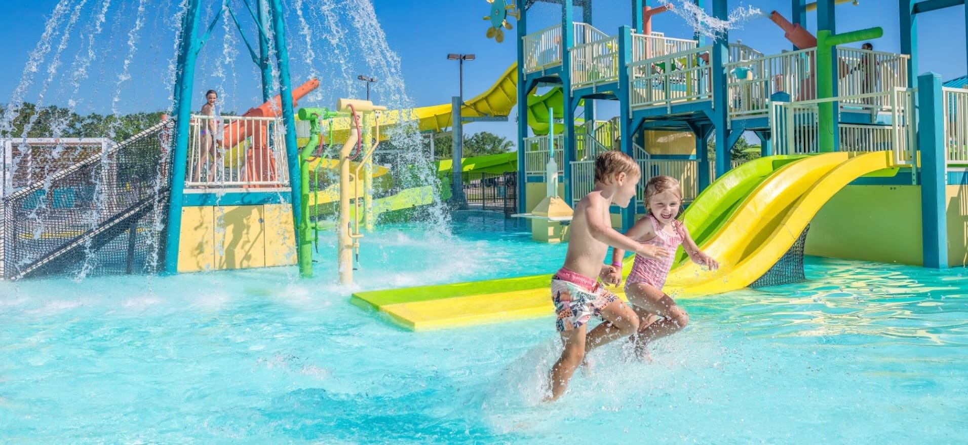 A boy and girl playing at a water play park