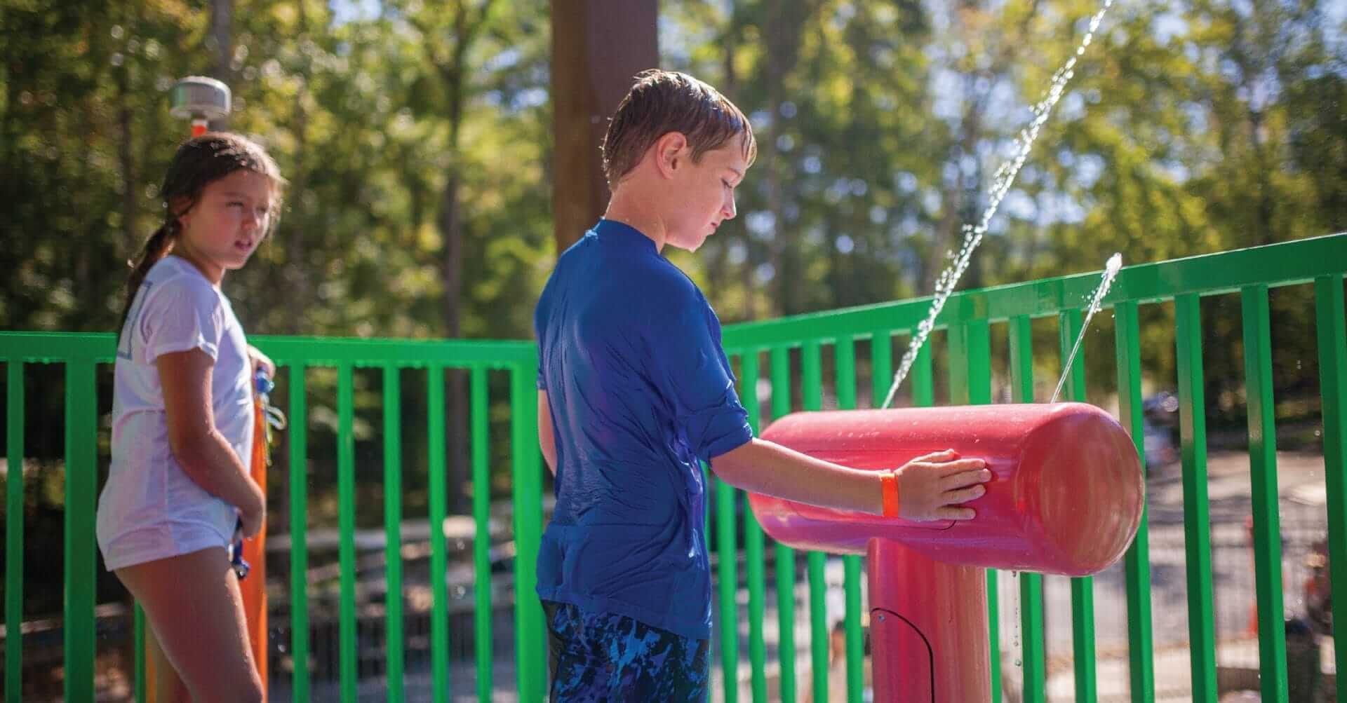 A young boy activates the Thump Pump water play feature by waiving his hand over the proximity sensor.