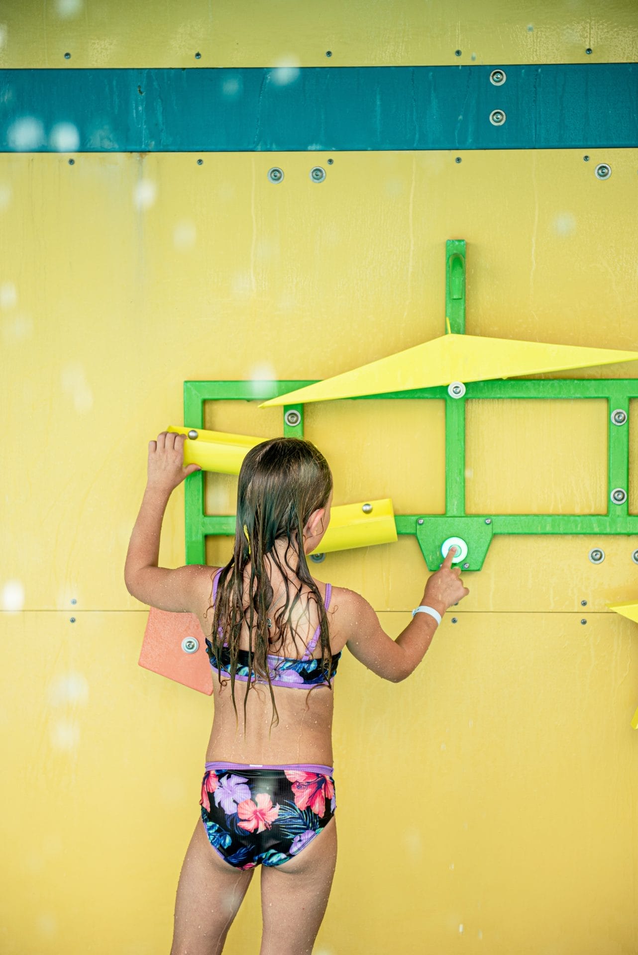 A girl pushes the light up touch sensor button to activate the water flow on the puddle juggle water play feature by Interactive Play.