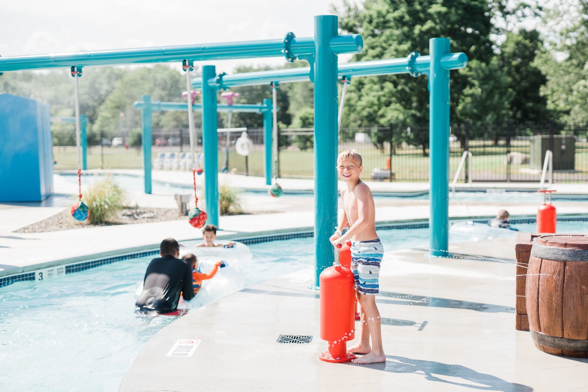 A boy playing with an Interactive Play thump pump next to a lazy river