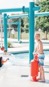 Boy playing with an interactive play thump pump at a water play park
