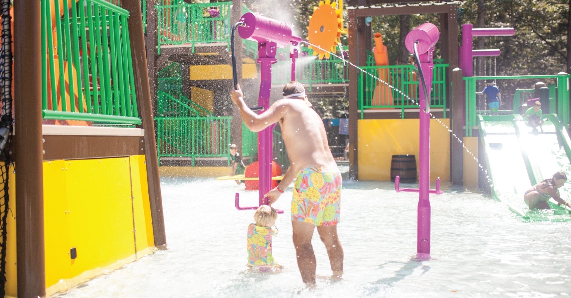 A dad and toddler activating the beanstalk blaster shooting a stream of water towards another water player at the waterpark in Bostic, North Carolina.