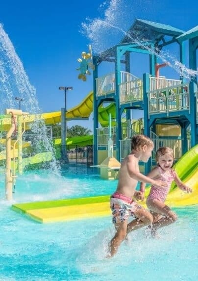 Kids run through the water as interactive water spray features by Interactive Play shoot water at the waterpark at Camp Margaritaville in Henderson, LA.