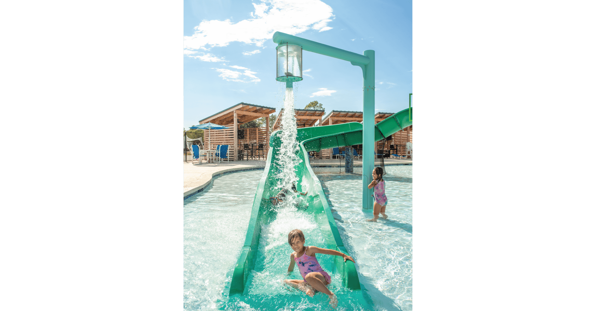 Kid activates the pour over water feature releasing water on another patron coming down the water slide at the Jellystone in Waller, Texas.