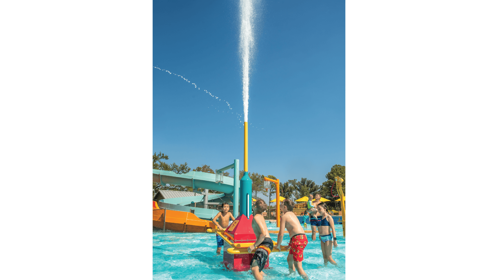 Kids working together to activate the rainmaker waterplay feature by Interactive Play as a large burst of water shoots into the sky.
