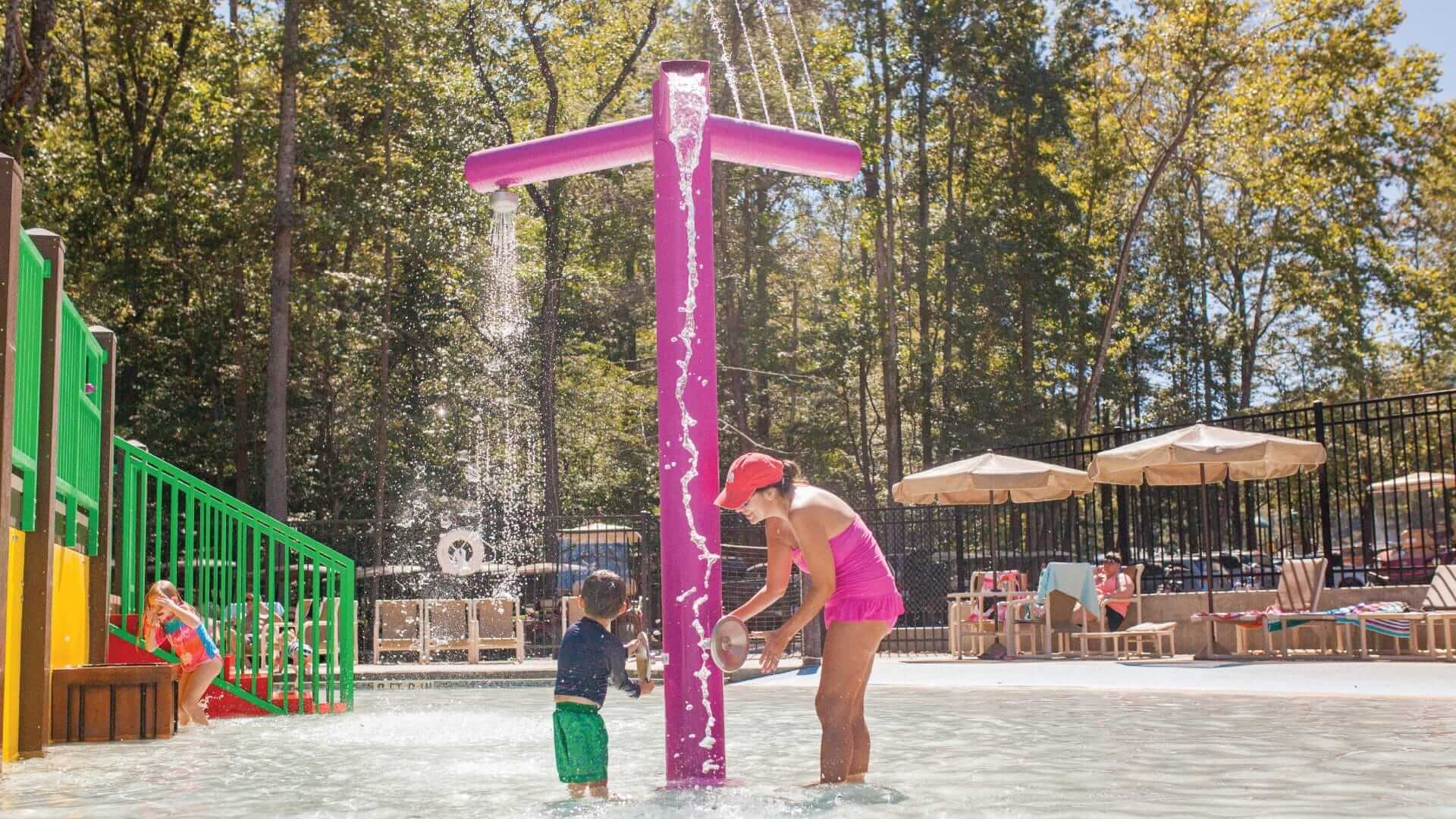 Kid activating the three tree water play feature at a waterpark.